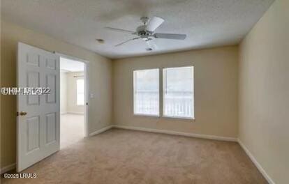 carpeted empty room featuring ceiling fan and baseboards