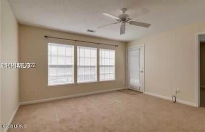 carpeted spare room featuring a ceiling fan and baseboards