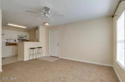 spare room with carpet floors, baseboards, and a ceiling fan