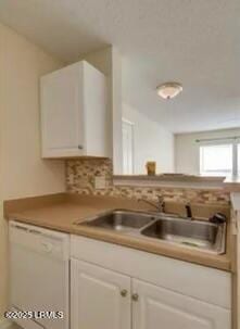 kitchen with decorative backsplash, white cabinets, white dishwasher, and a sink