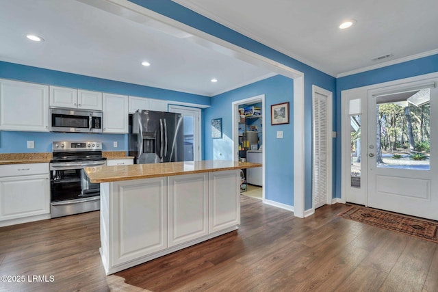 kitchen featuring dark wood-type flooring, stainless steel appliances, a center island, and white cabinets