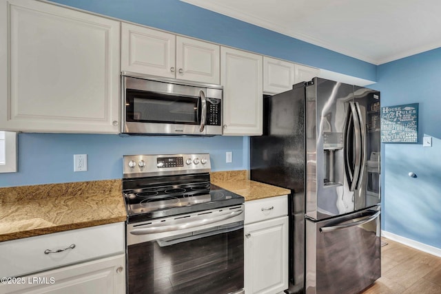 kitchen featuring crown molding, appliances with stainless steel finishes, light hardwood / wood-style floors, white cabinets, and dark stone counters