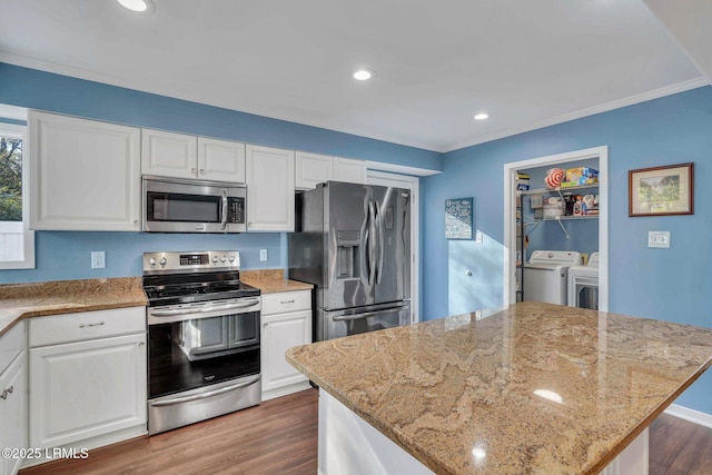 kitchen with washer and dryer, white cabinetry, a center island, light stone counters, and stainless steel appliances