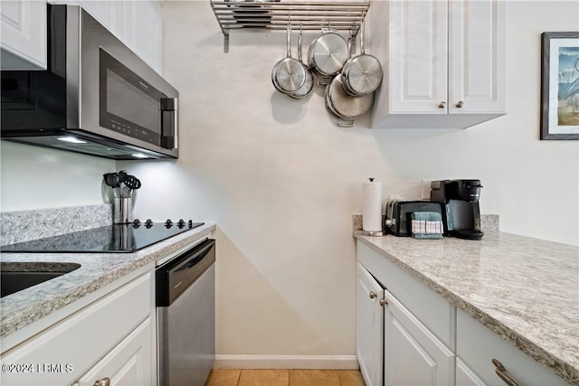 kitchen with light tile patterned floors, light stone countertops, white cabinets, and appliances with stainless steel finishes