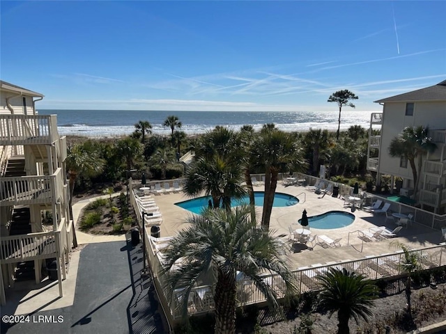 view of pool featuring a water view, a view of the beach, and a patio area