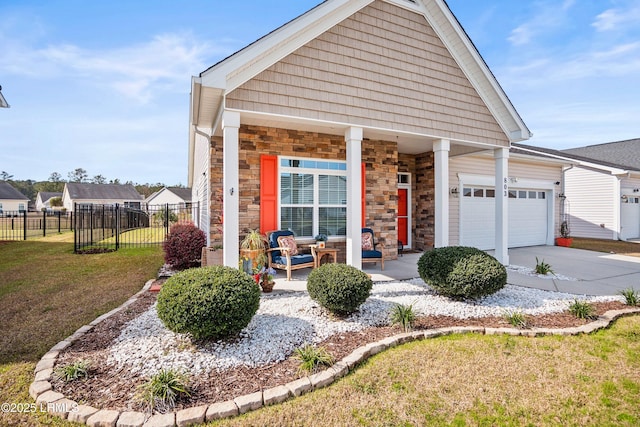 view of front of house with concrete driveway, stone siding, covered porch, fence, and a front yard