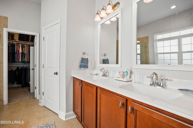 full bath featuring a spacious closet, double vanity, tile patterned flooring, and a sink