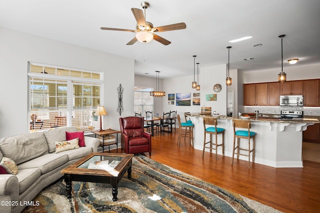 living room with a ceiling fan, visible vents, and wood finished floors