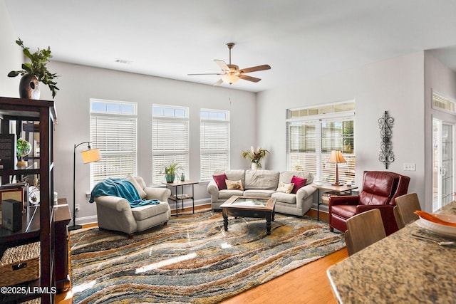 living area with a healthy amount of sunlight, a ceiling fan, visible vents, and wood finished floors