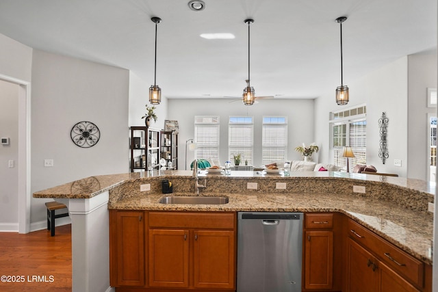 kitchen with a sink, brown cabinetry, dishwasher, and decorative light fixtures