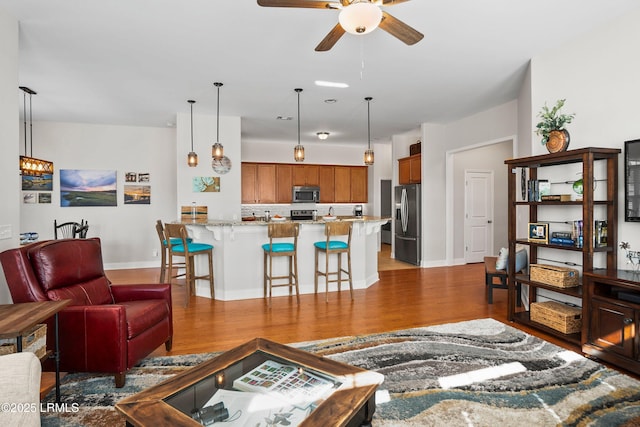 living area with ceiling fan, baseboards, and wood finished floors