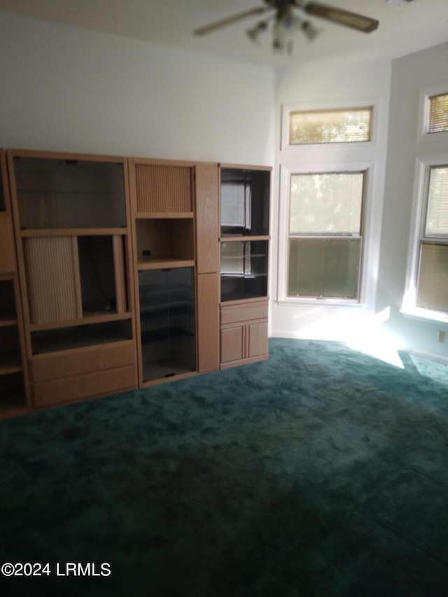 unfurnished living room featuring carpet floors and a ceiling fan