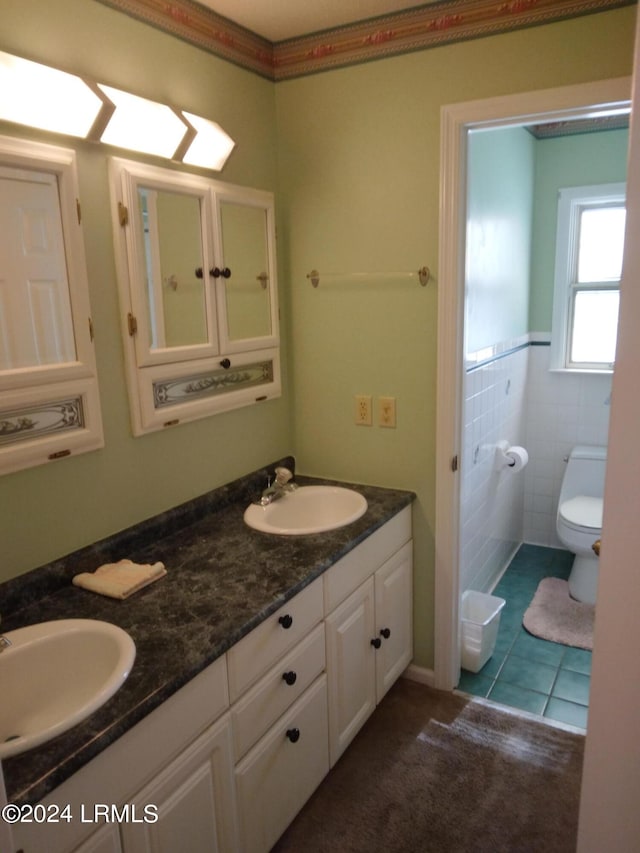 bathroom with toilet, tile patterned flooring, double vanity, and a sink