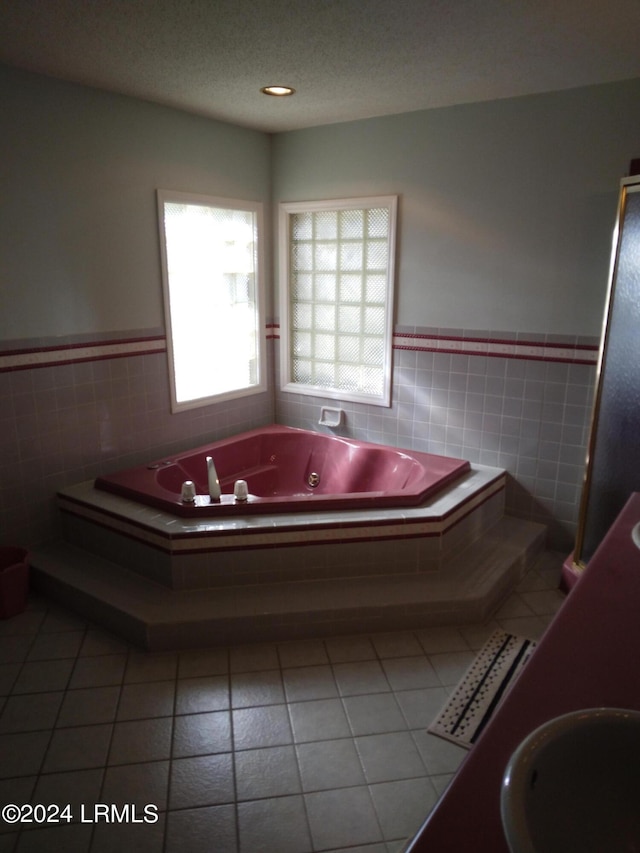 bathroom with a wainscoted wall, tile walls, a tub with jets, and tile patterned floors