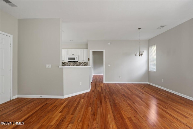 unfurnished living room featuring wood-type flooring and a chandelier