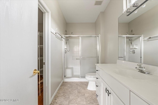 bathroom featuring vanity, a shower with shower door, and toilet