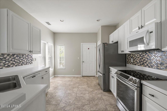 kitchen with stainless steel appliances, sink, white cabinets, and backsplash