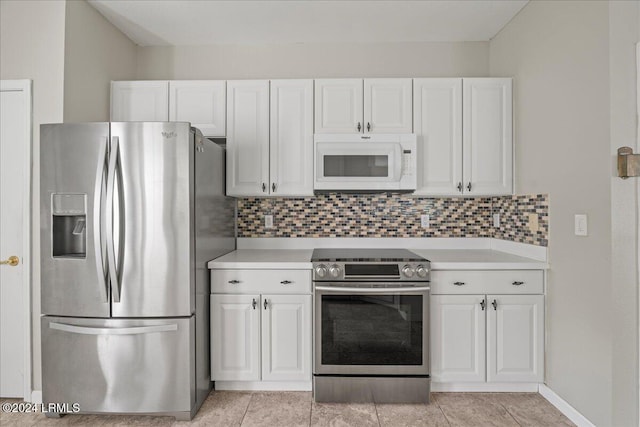 kitchen featuring appliances with stainless steel finishes, light tile patterned floors, white cabinets, and decorative backsplash