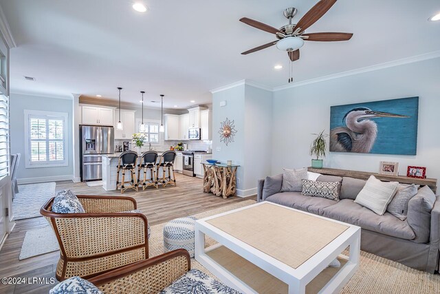 living room featuring crown molding, light hardwood / wood-style floors, and ceiling fan