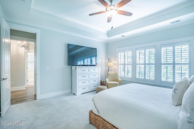 carpeted bedroom with a tray ceiling, ornamental molding, and ceiling fan