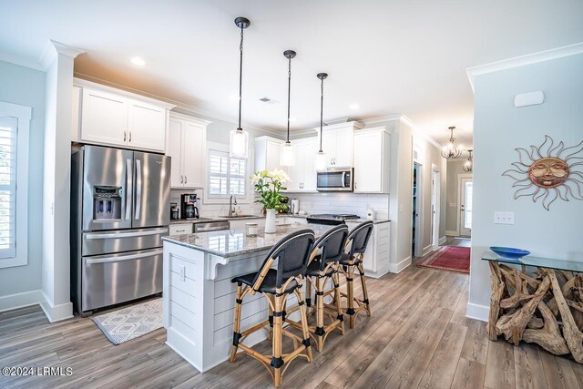 kitchen with light stone countertops, stainless steel appliances, a center island, and white cabinets