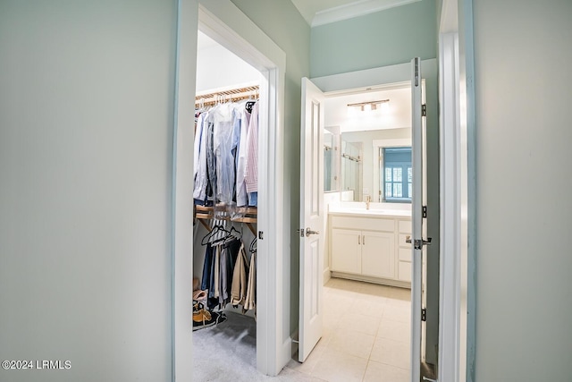 corridor with crown molding, sink, and light tile patterned floors