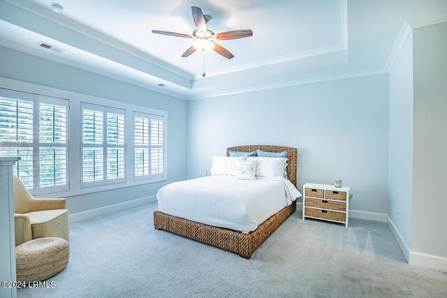 carpeted bedroom with crown molding, ceiling fan, and a raised ceiling