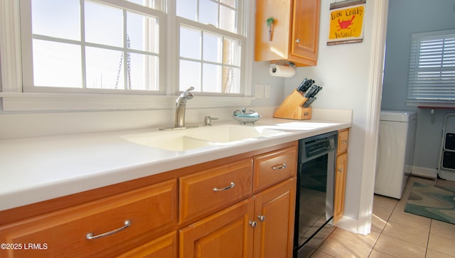 kitchen featuring light tile patterned floors, a sink, light countertops, black dishwasher, and brown cabinetry