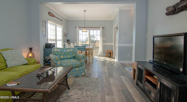 living area with wood finished floors, ornamental molding, and baseboards