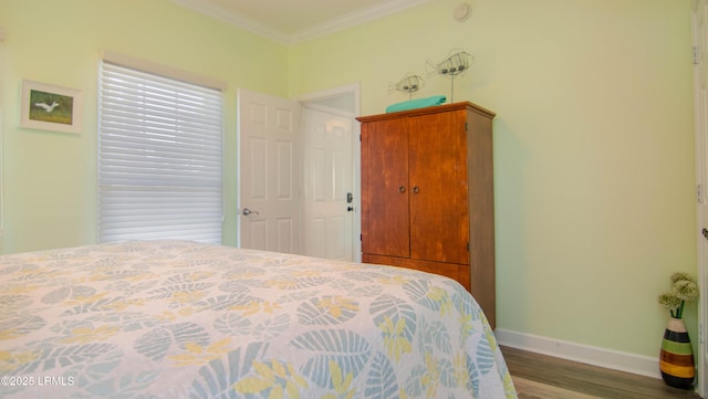 bedroom featuring wood finished floors, crown molding, and baseboards