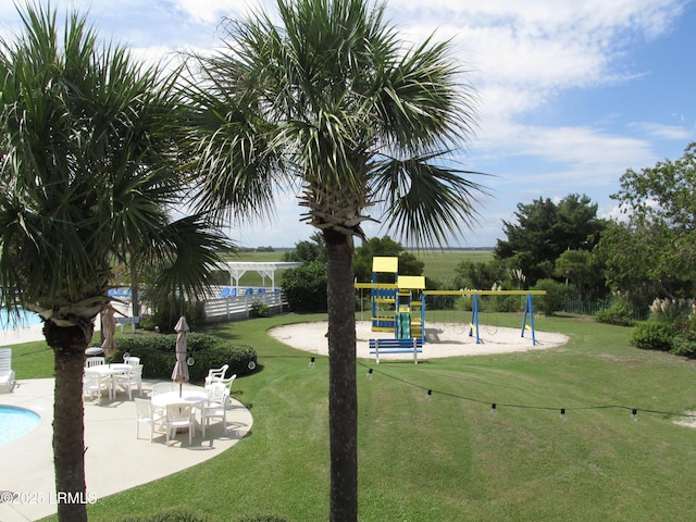 view of home's community with a yard, a patio, playground community, and fence