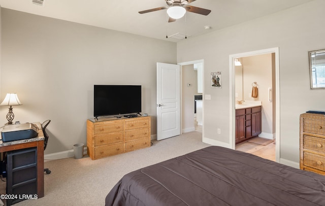 bedroom featuring ceiling fan, light colored carpet, and ensuite bath