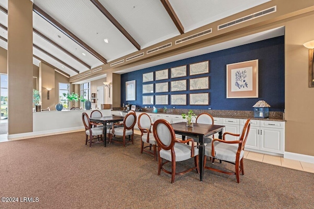 dining space featuring high vaulted ceiling, light colored carpet, and beam ceiling