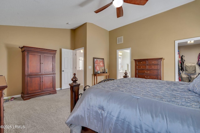 bedroom with vaulted ceiling, light carpet, connected bathroom, and ceiling fan