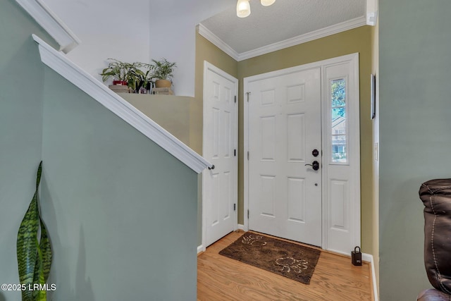 entrance foyer featuring crown molding, a textured ceiling, and light hardwood / wood-style flooring