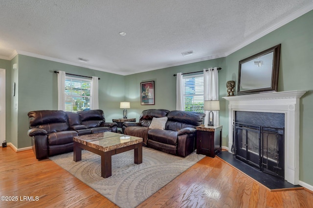 living room featuring crown molding, plenty of natural light, a textured ceiling, and light wood-type flooring