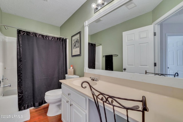 full bathroom featuring hardwood / wood-style flooring, vanity, shower / tub combo, toilet, and a textured ceiling