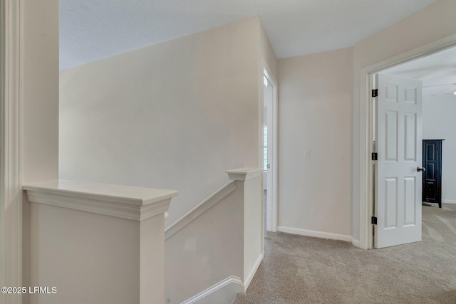 hall with light carpet and a textured ceiling