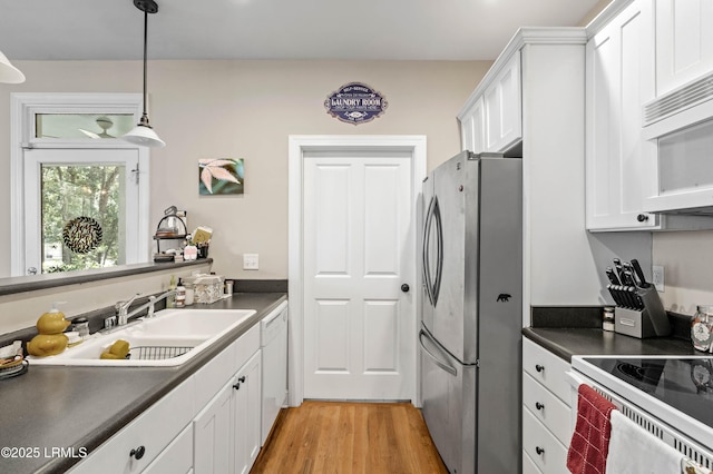2654 Broad St, Beaufort, SC 29902 - kitchen featuring white appliances, dark countertops, white cabinets, a sink, and light wood-type flooring