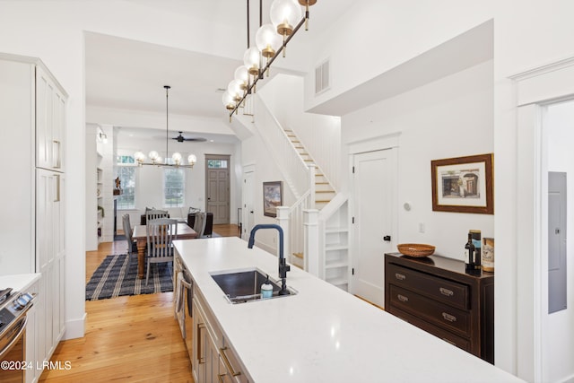 kitchen featuring sink, an inviting chandelier, hanging light fixtures, stainless steel range oven, and light wood-type flooring