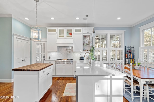 kitchen with stainless steel gas cooktop, tasteful backsplash, butcher block counters, ornamental molding, and dark wood-type flooring