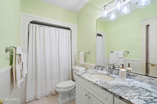 full bath with a wainscoted wall, vanity, toilet, and tile patterned floors