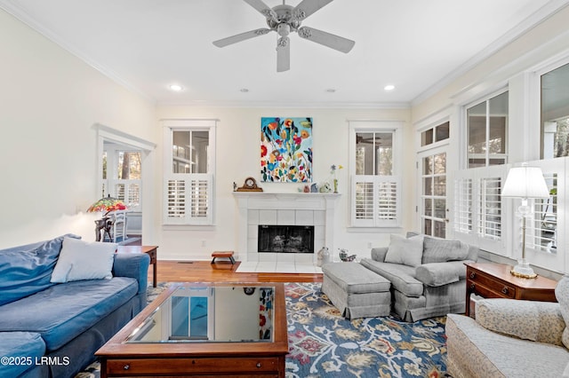 living area with recessed lighting, a tiled fireplace, crown molding, and wood finished floors