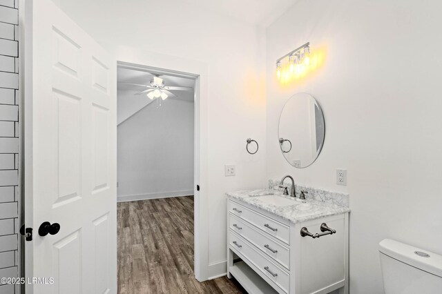 bathroom featuring toilet, ceiling fan, wood finished floors, and vanity