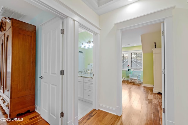 corridor with visible vents, light wood-style flooring, and baseboards