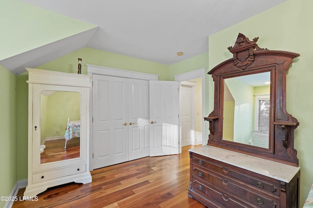 bedroom with lofted ceiling, a closet, and light wood-type flooring