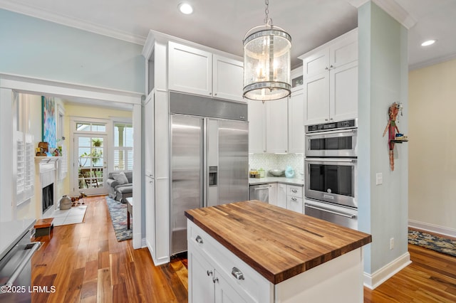 kitchen with wood counters, an inviting chandelier, stainless steel appliances, crown molding, and a warming drawer