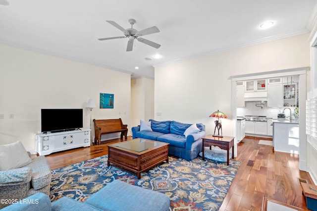 living area featuring crown molding, ceiling fan, wood finished floors, and recessed lighting