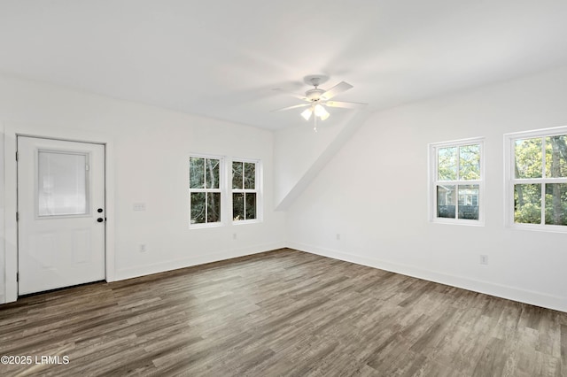 interior space with dark wood finished floors, a ceiling fan, and baseboards