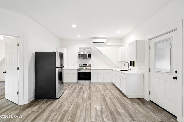 kitchen with a sink, light wood-style floors, an AC wall unit, appliances with stainless steel finishes, and light countertops